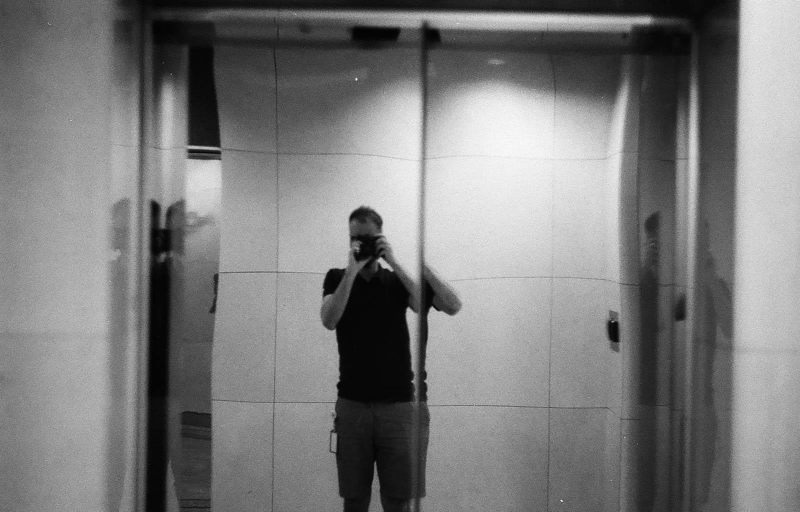 Человек фотографирует себя в отражении лифта