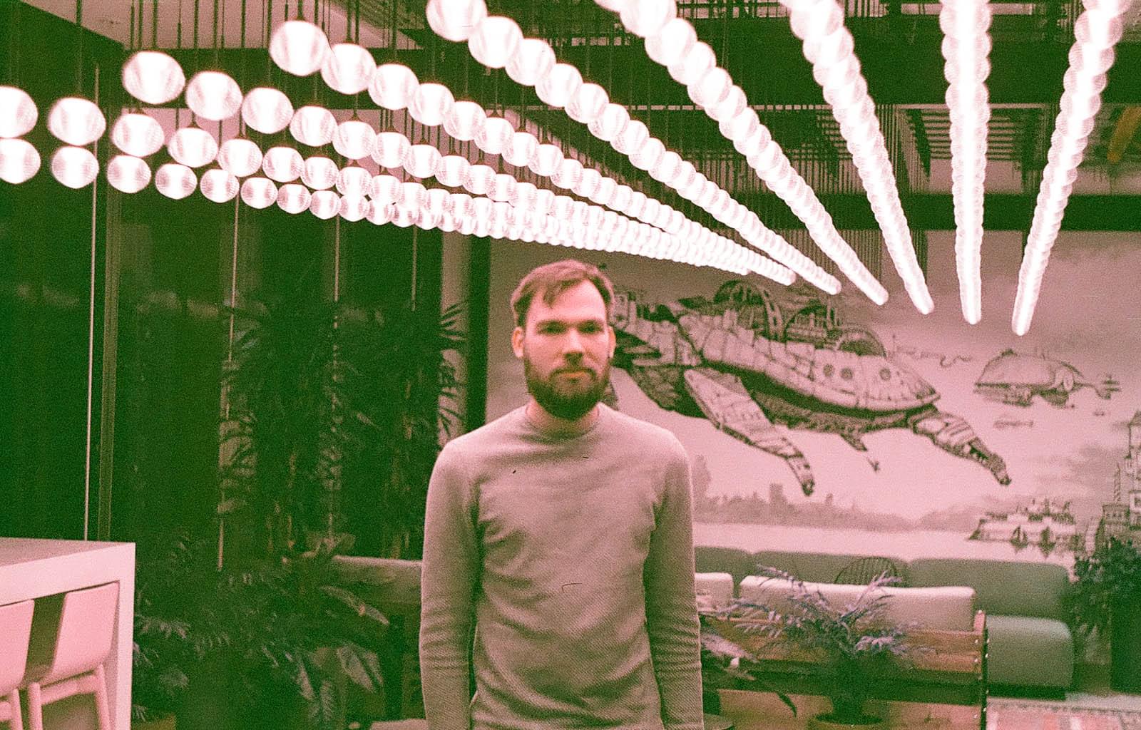 Дизайнер позирует на фоне стены с летящей черепахой