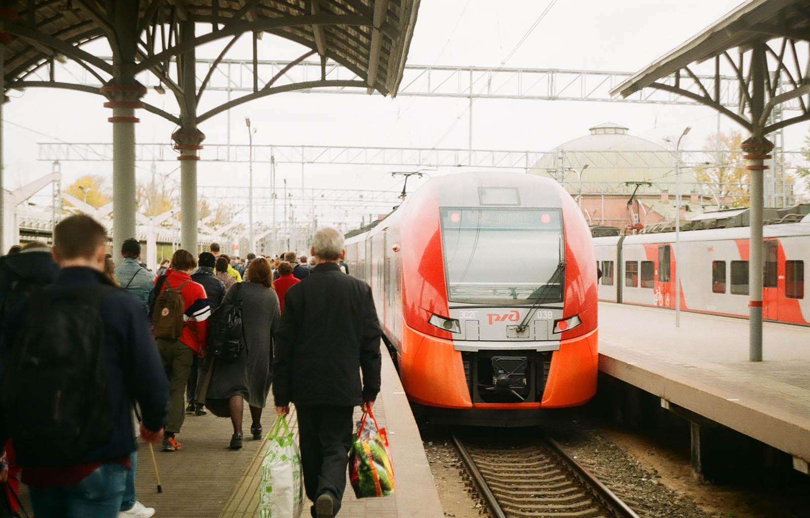 Большая группа людей идёт на встречу электричке