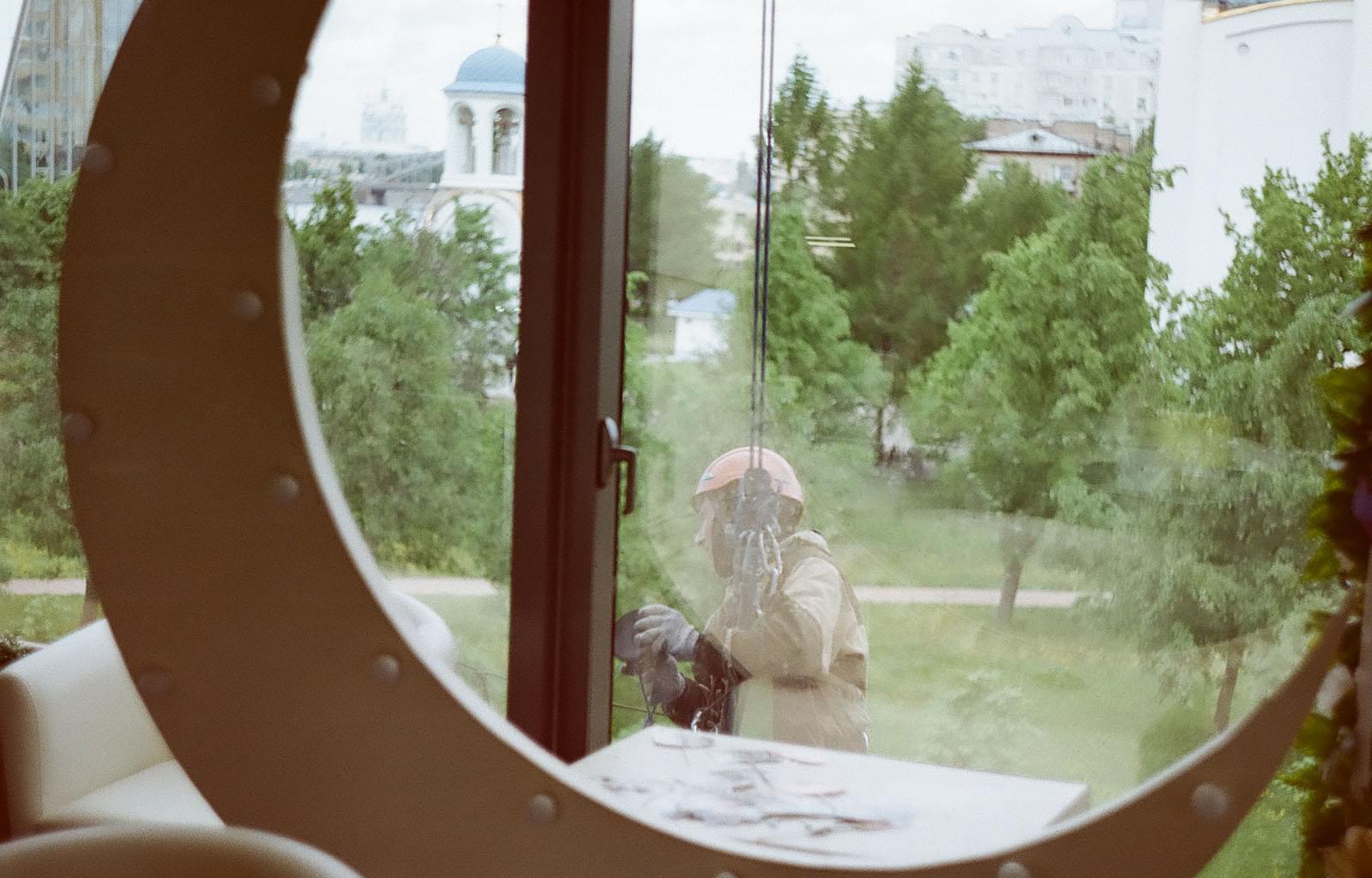 Мойщик окон на тросе за окном