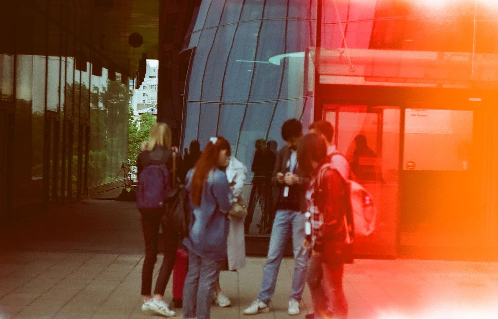 Группа людей перед стеклянными стенами здания